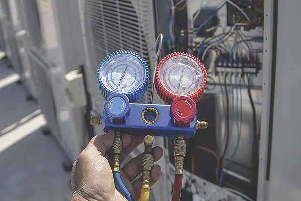 TW1026_HVAC service technician using gauges to check and add refrigerant.jpg