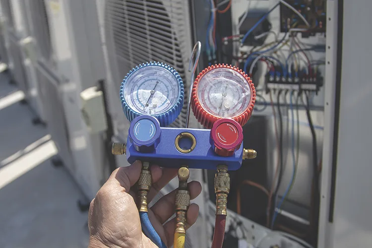 TW1026_HVAC service technician using gauges to check and add refrigerant.jpg