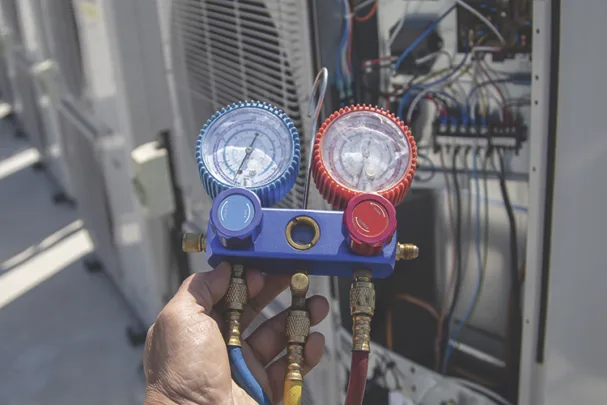 TW1026_HVAC service technician using gauges to check and add refrigerant.jpg